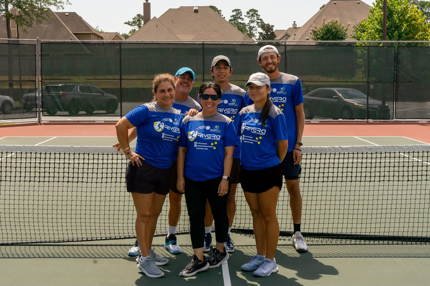 The six coaches of Rivera Tennis Academy standing together at the net on an outdoor hard court.