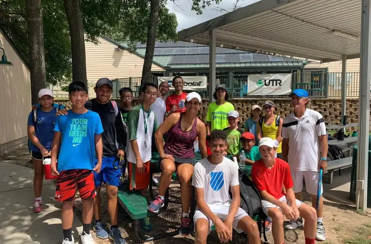 Junior players and coaches on the courts at Rivera Tennis Academy in Spring, Texas.
